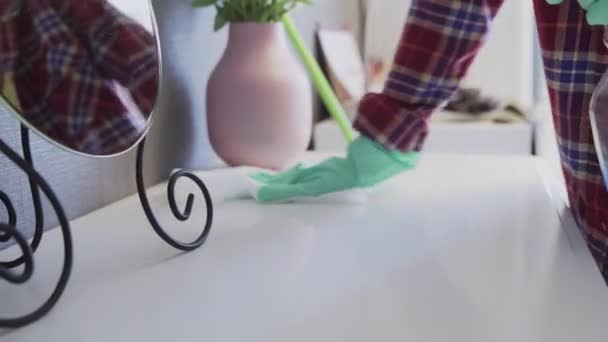 Jonge vrouw met een witte doek om stof van de tafel te verwijderen — Stockvideo