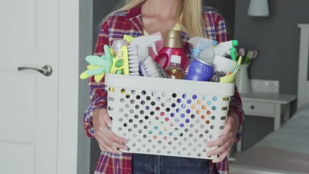 Mujer irreconocible con la cesta llena de esponjas y productos químicos del hogar mirar a la cámara — Vídeo de stock