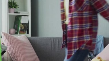 Eldivenli gülümseyen kadın kanepede oturuyor, ev temizliğinden sonra dinleniyor.