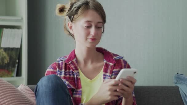 Piękna młoda kobieta spoczywa na kanapie po sprzątaniu i korzystaniu z telefonu — Wideo stockowe