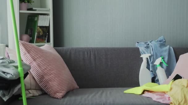 Exhausted woman in gloves sitting on sofa, relaxing after house cleaning work — Stock Video