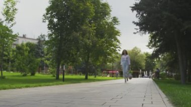 Kadın elinde sebzelerle pamuk ağıyla alışveriş çantası tutuyor ve yaz parkında yürüyor. Sıfır atık.
