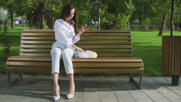 Mujer joven se sienta en el banco con bolsa de compras de malla de algodón llena de frutas y verduras en el parque de verano. Compra cero residuos . — Vídeo de stock