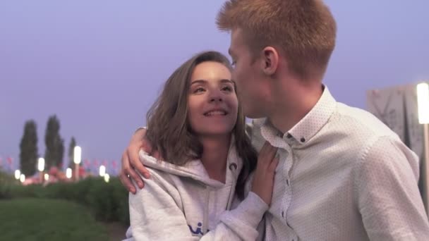 Young lovely couple sits and talks in the summer park in the evening — Stock Video