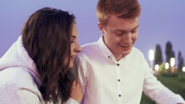 Young lovely couple sits and talks in the summer park in the evening — Stock Video