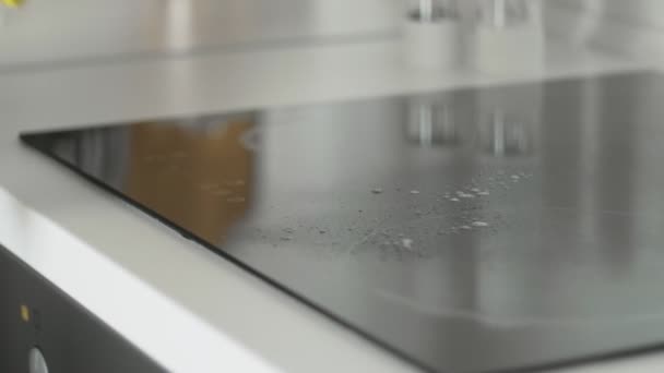 Limpar o painel de cozinha da placa de cozinhar na cozinha com spray removedor de gordura e pano amarelo por uma mulher em luvas de borracha amarela . — Vídeo de Stock