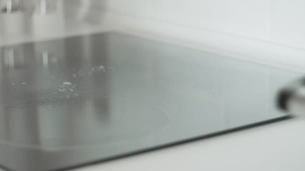 Cleaning cooktop cooking panel in kitchen with fat remover spray and pink rag by a woman in yellow rubber gloves. — Stock Video