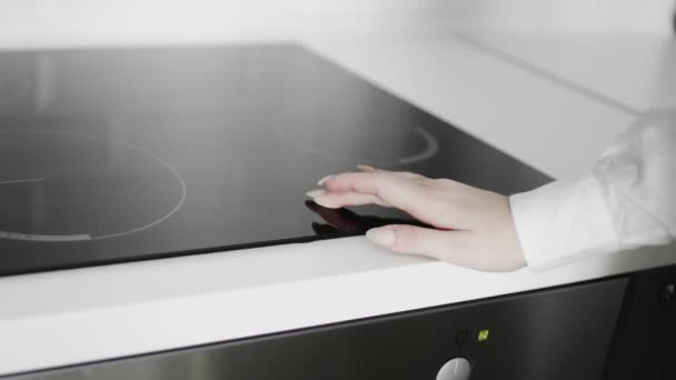 Close up of a female hand turned on induction cooker — Stock Video