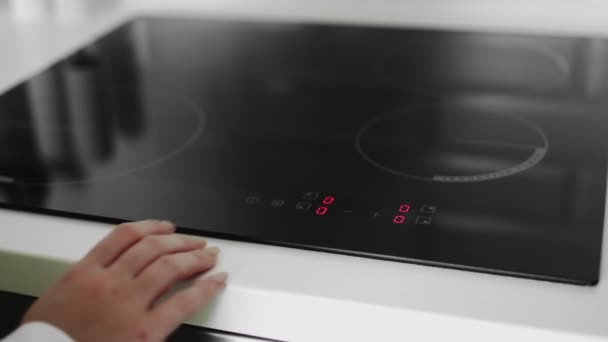 Gros plan d'une main féminine allumée sur une cuisinière à induction — Video