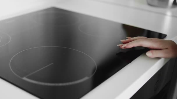 Крупним планом жіноча рука включена в індукційну плиту — стокове відео