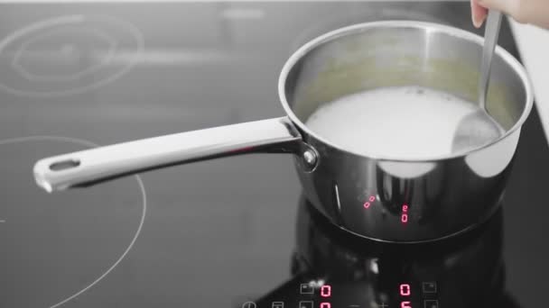 De koemelk kookt in een pan. Vrouw roert melk in steelpan — Stockvideo
