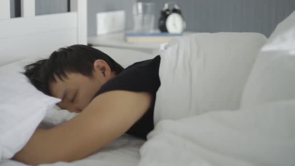 若いアジア人の男の閉じる嘘と家のベッドで寝て. — ストック動画