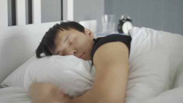 若いアジア人の男の閉じる嘘と家のベッドで寝て. — ストック動画