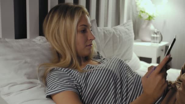 Femme couchée sur un lit utilise une tablette d'ordinateur — Video