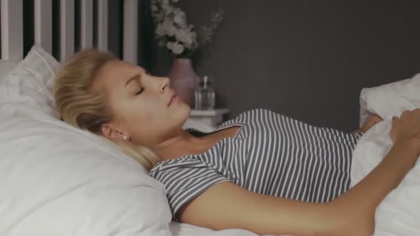 Młoda kobieta leżąca w nocy w łóżku. Piękna blondynka śpiąca. Kobieta ma zły sen. — Wideo stockowe