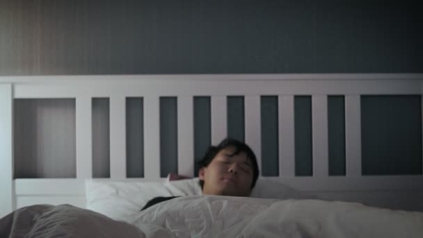 Sleepy junge asiatische Mann aufwachen nach oben in die Bett zu Hause. — Stockvideo