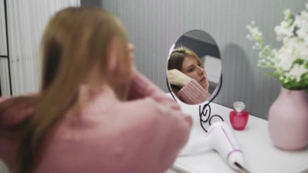 Όμορφη νεαρή γυναίκα χρησιμοποιεί ένα στεγνωτήρα μαλλιών, ενώ κοιτάζοντας στον καθρέφτη στο δωμάτιο — Αρχείο Βίντεο