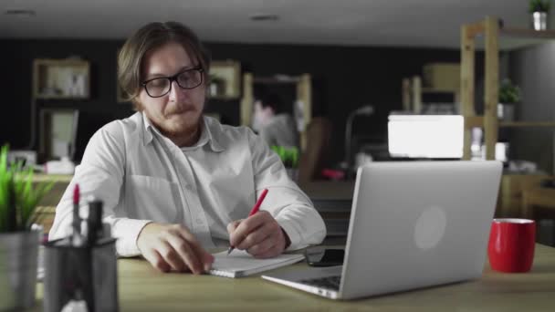 Biznesmen pracuje w biurze, pisząc samotnie przy biurku. — Wideo stockowe
