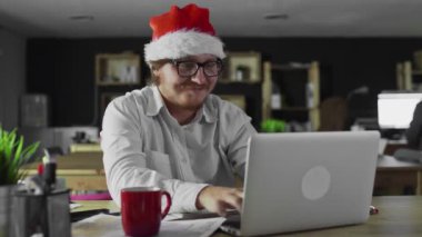 Müdürün keyfi yerinde. Noel 'de ofiste dizüstü bilgisayarla çalışıyor.