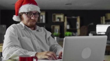 Genç ve yorgun müdür Noel 'de ofiste çalışıyor ve çay içiyor.