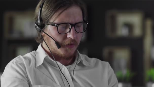 Менеджер в навушниках працює за столом тільки в офісі — стокове відео
