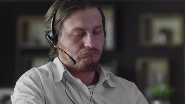 Kulaklıklı genç müdür ofiste çalışıyor. Akıllı telefonlara bakıyor. — Stok video