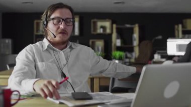 Kulaklıklı genç müdür ofisteki akıllı telefona bakıyor.