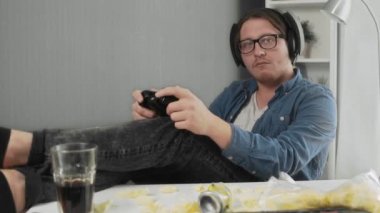Genç adam kanepede oturmuş video oyunları oynuyor..