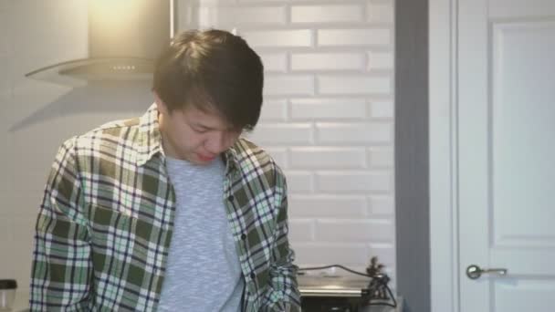 Jovem asiático homem bocejando e bebendo café turco na cozinha em casa — Vídeo de Stock