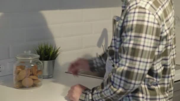 Aziatische man eten een koekje thuis in de keuken. — Stockvideo