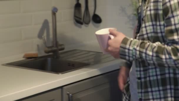 Close-up van aziatische man het nemen van een koekje en het drinken van koffie thuis in de keuken. — Stockvideo