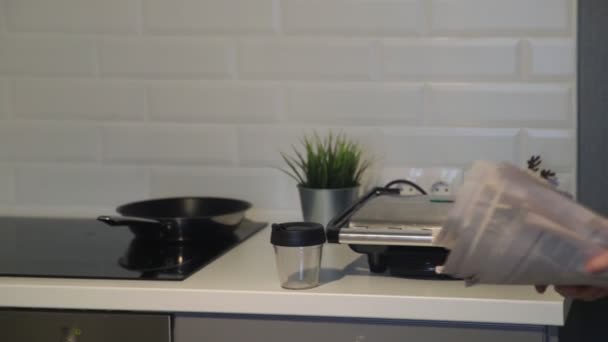 Close up of sleepy asian man with newspaper taking a cookie at home in the kitchen. — Stock Video