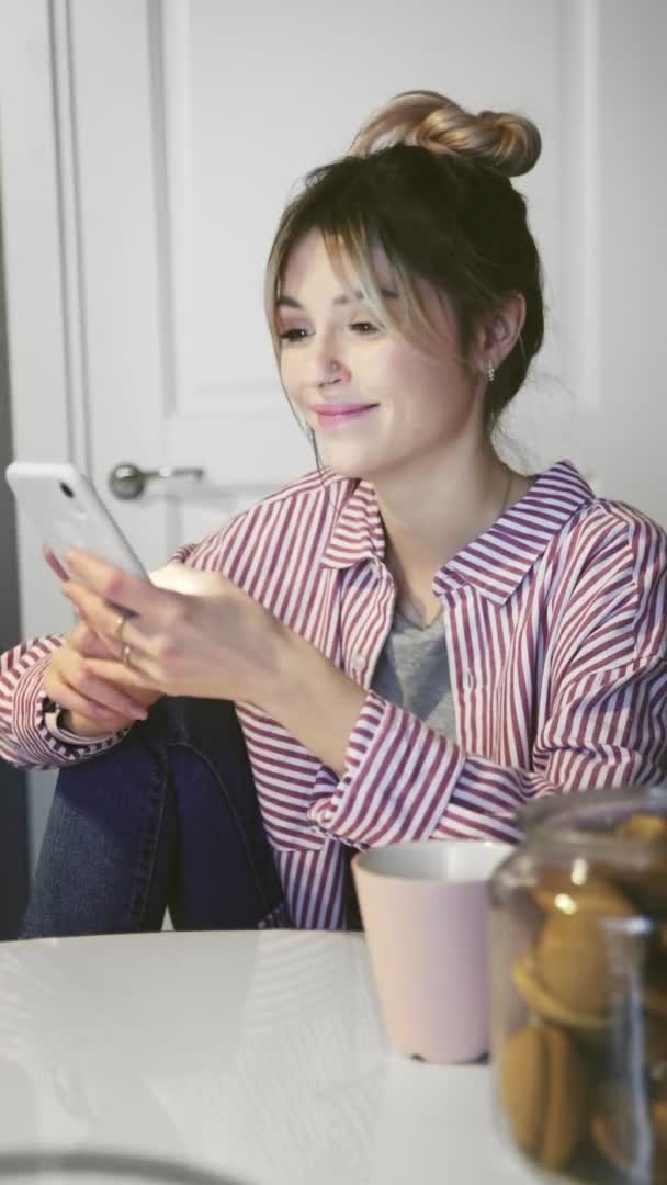 Vidéo verticale de la jeune femme souriante tapant, faisant défiler et tapant sur le smartphone — Video