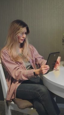 Çekici kadının mutfakta dijital tablet kullandığı dikey video.