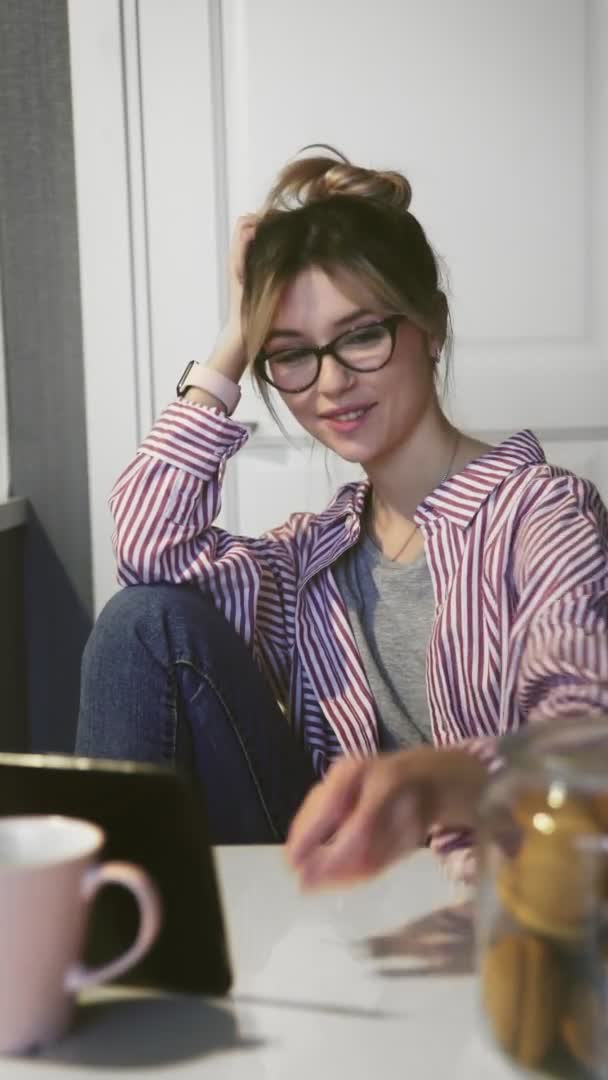 Vídeo vertical de la mujer feliz viendo un vídeo divertido en la tableta digital en la cocina — Vídeo de stock