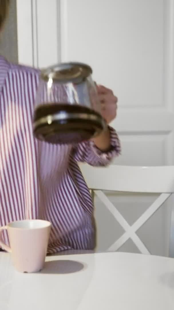 Video verticale di giovane bella donna bruna versa e beve caffè a casa in cucina — Video Stock