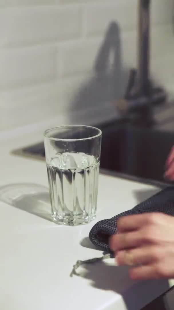 Вертикальное видео женщины кладет бамбуковую соломинку в стакан с водой — стоковое видео