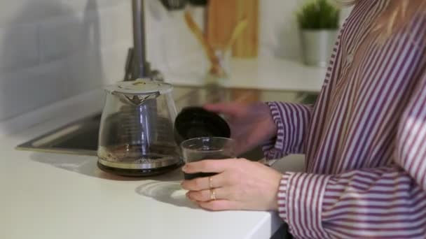 Close-up van jonge vrouw schenkt koffie in herbruikbare kopje naar huis te gaan in de keuken — Stockvideo