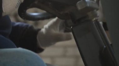 Forklift yükleme kabininde direksiyona dönen üniformalı işçiler çok yakından görülür..