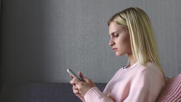 Nahaufnahme einer traurigen jungen Frau, die eine schlechte Nachricht liest und das Telefon wirft, während sie zu Hause auf dem Sofa sitzt — Stockvideo