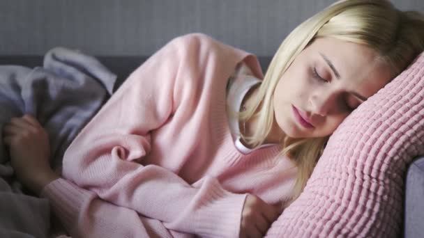 A fiatal, gyönyörű nőt telefonhívással ébresztették fel, de újra elaludt. Nő szundikál a kanapén a nappaliban — Stock videók
