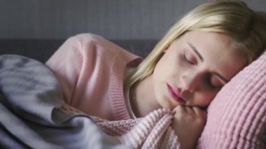 Genç ve güzel bir kadın oturma odasında kanepede uyanıyor.