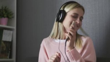 Kulaklık takan, mutlu müzik dinleyen ve kanepede dans eden bir kadın.