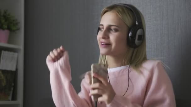 Close up de mulher usando fones de ouvido ouvindo música feliz e dançando no sofá — Vídeo de Stock