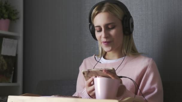 Mladá žena sedí na gauči jí tousty a sledovat video na smartphone — Stock video