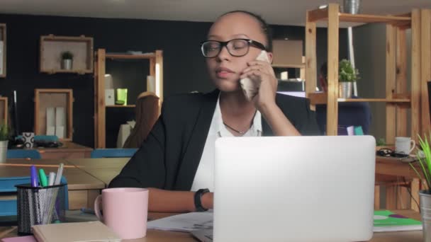 Ung afrikansk amerikansk kvinna talar i telefon i coworking office — Stockvideo