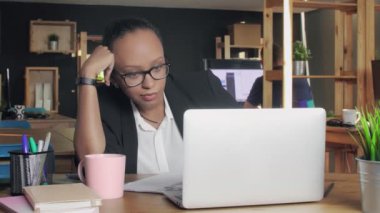 Sıkılmış Afrikalı Amerikalı kadın ofiste otururken uykulu hissediyor.