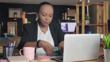 Genç Afro-Amerikan kadın ofiste öğle yemeği yiyor. Kadın sebze yemek istemiyor, çörek yemeye karar verdi.