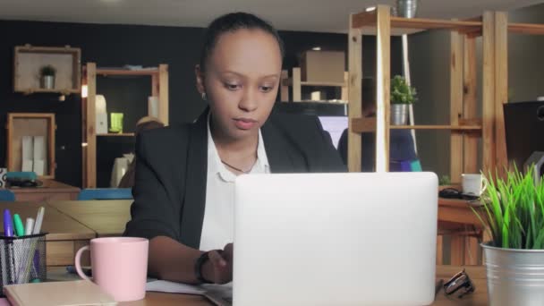 Junge Afroamerikanerin tippt auf Laptop und trinkt Kaffee aus rosa Tasse — Stockvideo