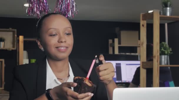 Primer plano de la gerente afroamericana feliz celebrando cumpleaños y pide un deseo en la oficina — Vídeo de stock